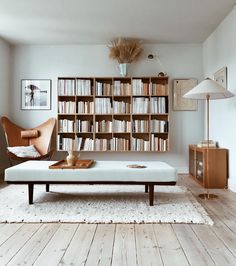 a living room filled with furniture and bookshelves next to a lamp on a table