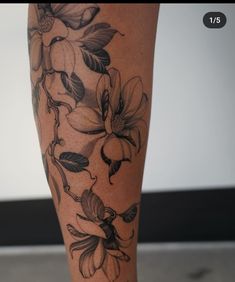 a woman's leg with flowers and leaves on it