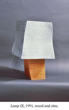 a lamp that is sitting on top of a wooden table next to a gray wall