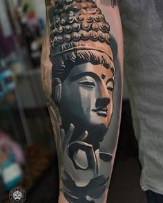 a man with a tattoo on his arm has an image of a buddha head in black and grey