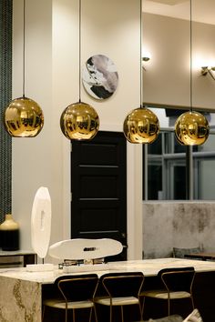 an elegant dining room with marble table and gold globe lights hanging from the ceiling above it