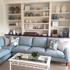 a living room with blue couches and white shelves