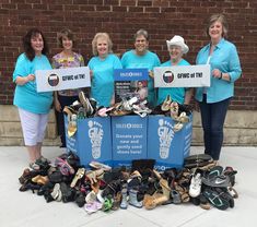 four women holding up signs in front of a pile of shoes