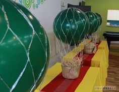 some green balloons are sitting on red and yellow tables