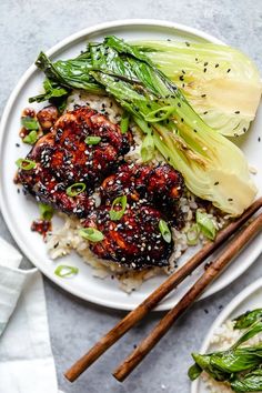 two white plates topped with food and chopsticks