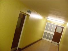 an empty hallway with yellow walls and doors