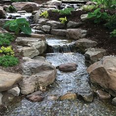 there is a small waterfall in the middle of this rock garden area with rocks and water running through it