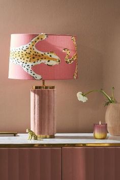 a pink lamp with a cheetah print on it next to two vases