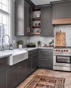 a kitchen with gray cabinets and white marble counter tops, an area rug on the floor