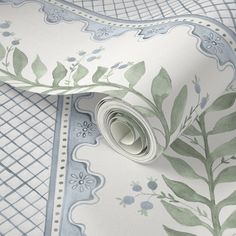 a wallpaper with green leaves and blue flowers on white paper, which is rolled up to the side