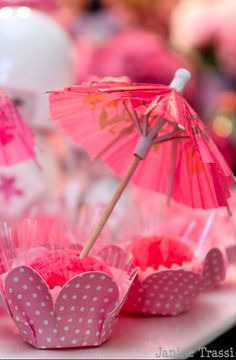 pink cupcakes and umbrellas are on the table