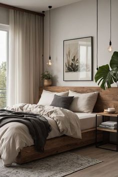 a bed sitting next to a window in a bedroom under two hanging lights and a plant