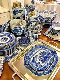 blue and white china is on display at a table with plates, silverware, and vases