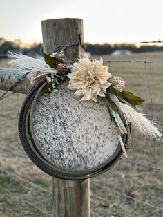 a cow hide with flowers and feathers hanging on it's side near a barbed wire fence