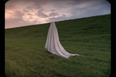 a white cloth draped in the grass on top of a hill