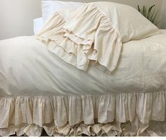 an unmade bed with white sheets and ruffles