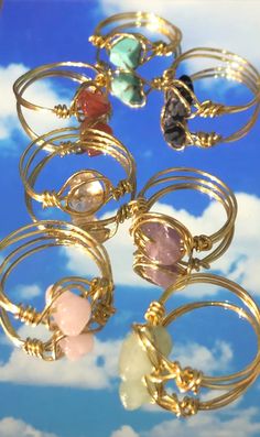 a bunch of rings with different colored stones on them in front of a blue sky