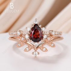 a close up view of a ring with a red stone in the center and white diamonds around it