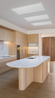 a large kitchen with wooden cabinets and white marble counter tops, along with an island in the middle