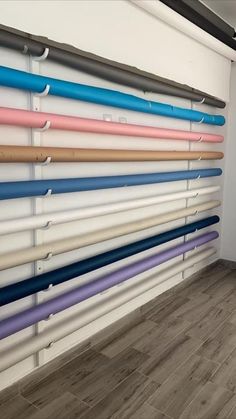 a wall with many different colored baseball bats on it's sides and in front of the wall is a wooden floor