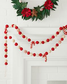 a christmas garland with candy canes and poinsettis hanging from the mantle