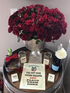 a bunch of red roses sitting on top of a wooden barrel next to wine bottles