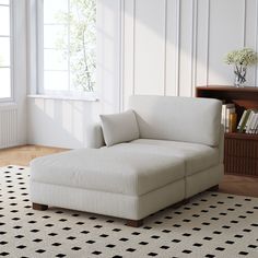 a white couch sitting on top of a black and white rug