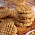 several peanut butter cookies stacked on top of each other next to a wooden cutting board