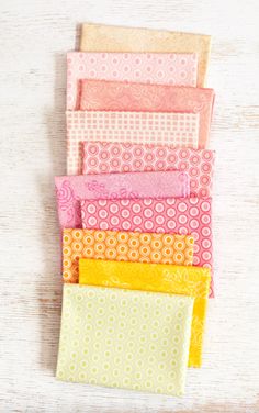 five different colors of fabric sitting on top of a white wooden table next to each other