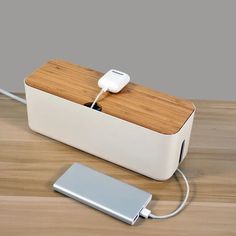 an electronic device is plugged into a charger on a wooden table with a charging cord