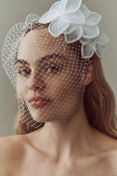 a woman wearing a white veil with flowers on the top and headpiece in front of her face