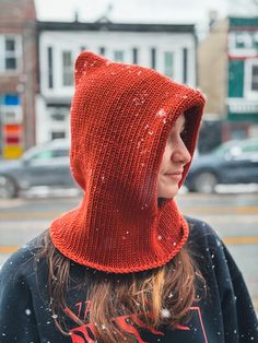 a woman wearing a red knitted hat and hood