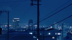 the city skyline is lit up at night, with power lines in the foreground