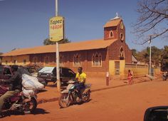 two people on motorcycles parked in front of a building with a clock tower behind them