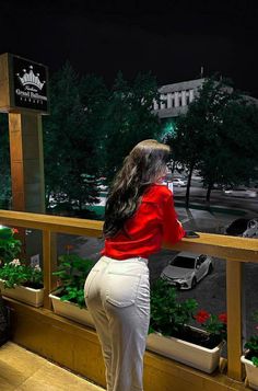 a woman standing on a balcony looking out at the street