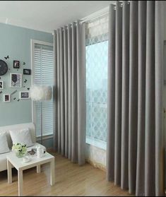 a living room with blue walls and white furniture in front of a window covered by grey curtains