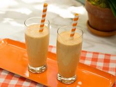 two glasses with orange and white straws on an orange tray