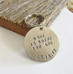 a metal keychain with the words home is where you are engraved on it