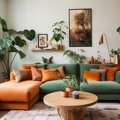 a living room filled with lots of green plants and orange pillows on top of a couch