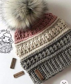 a crocheted hat with a pom - pom sitting on top of it