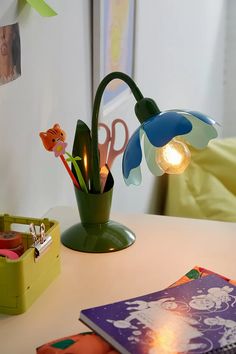 a green vase with flowers and scissors on a table next to an open book,