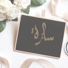 a close up of a sign with flowers and ribbon on the table next to it