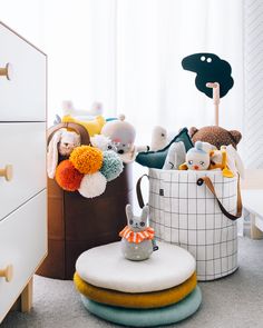 several stuffed animals are sitting in baskets on the floor next to a dresser and chair