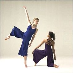 two young women in purple and blue dresses are doing yoga poses together, one is holding her leg up to the side