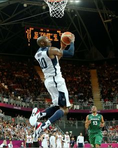 a basketball player jumping up into the air to dunk a ball in front of an audience