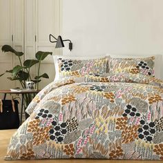 the comforter is made up with an orange and black floral pattern on it, along with matching pillows