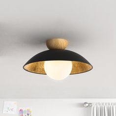 a black and gold light hanging from the ceiling in a room with white curtains on the window sill