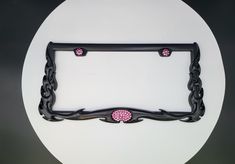 a decorative black frame with pink beads on the bottom and sides, hanging from a circular wall