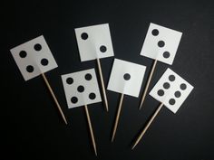 four pieces of white paper with black polka dots on them and toothpicks in the middle