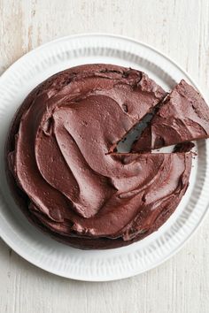 a chocolate cake on a white plate with a piece missing from it's side